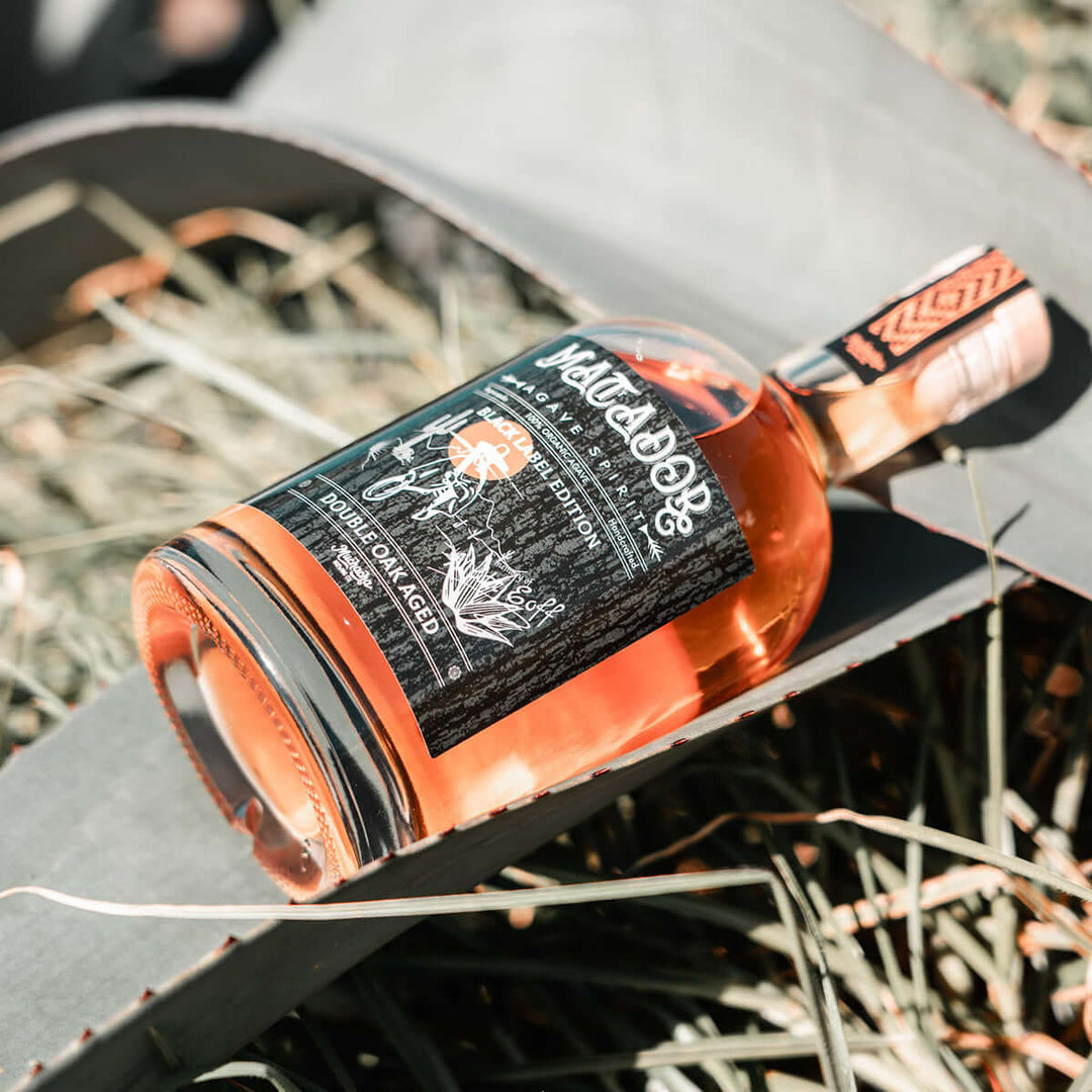 Tequila anejo bottle with a black label on an agave plant