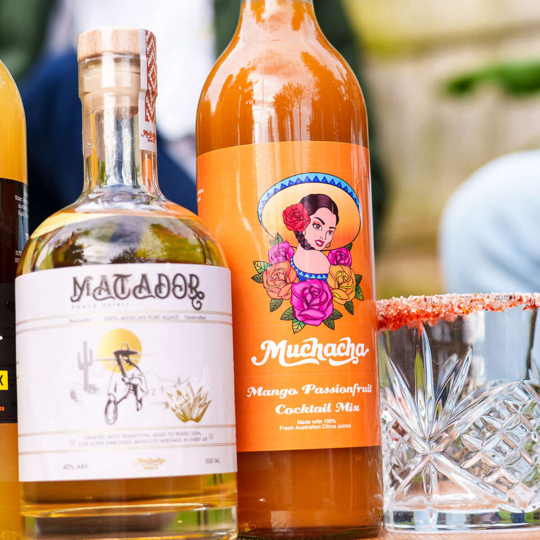 Bottles of Matador tequila and Muchacha mango  passionfruit cocktail mix with a cocktail glass.